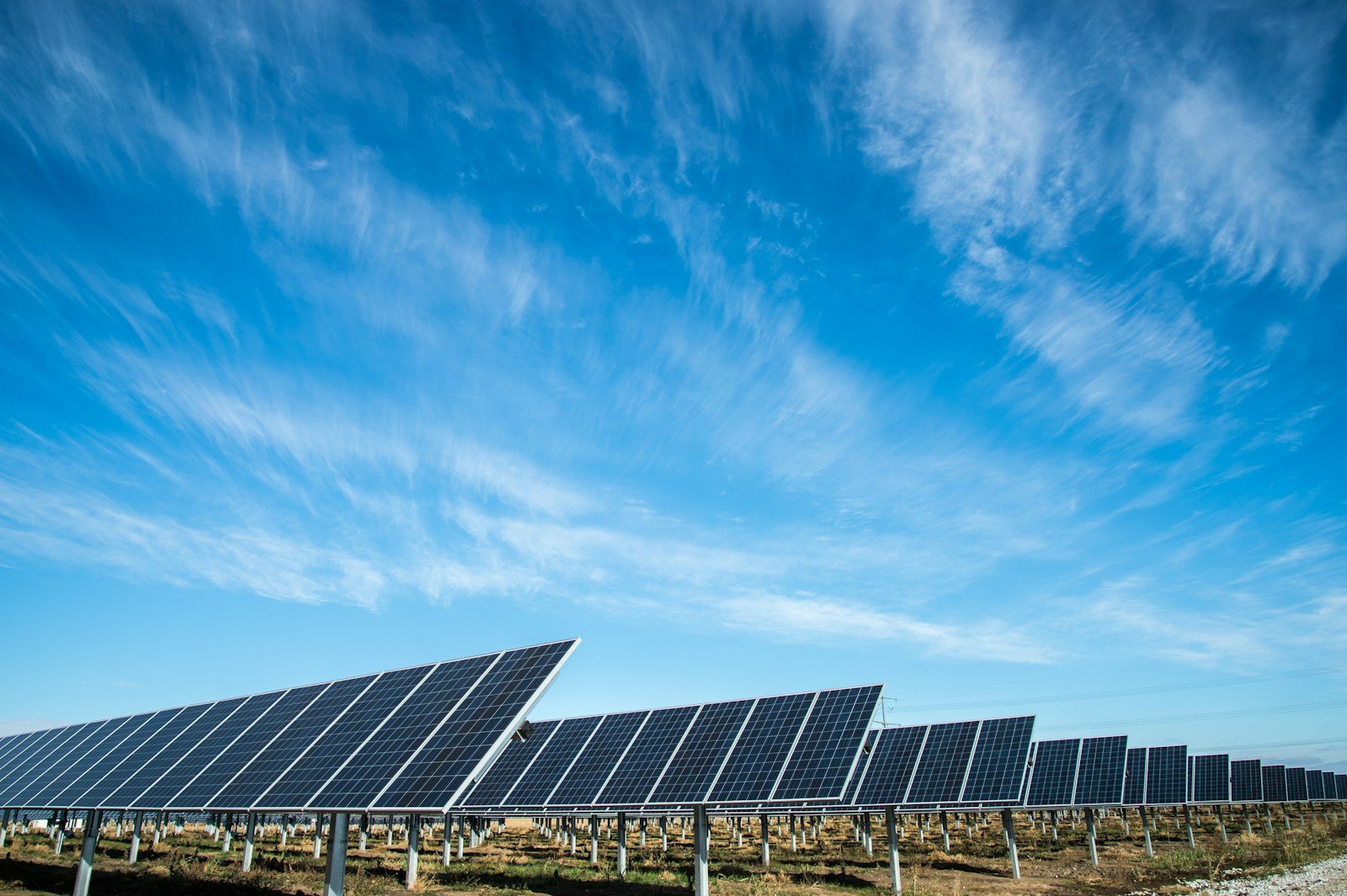 Rows of solar panels under a blue sky; illustrative Unsplash photograph